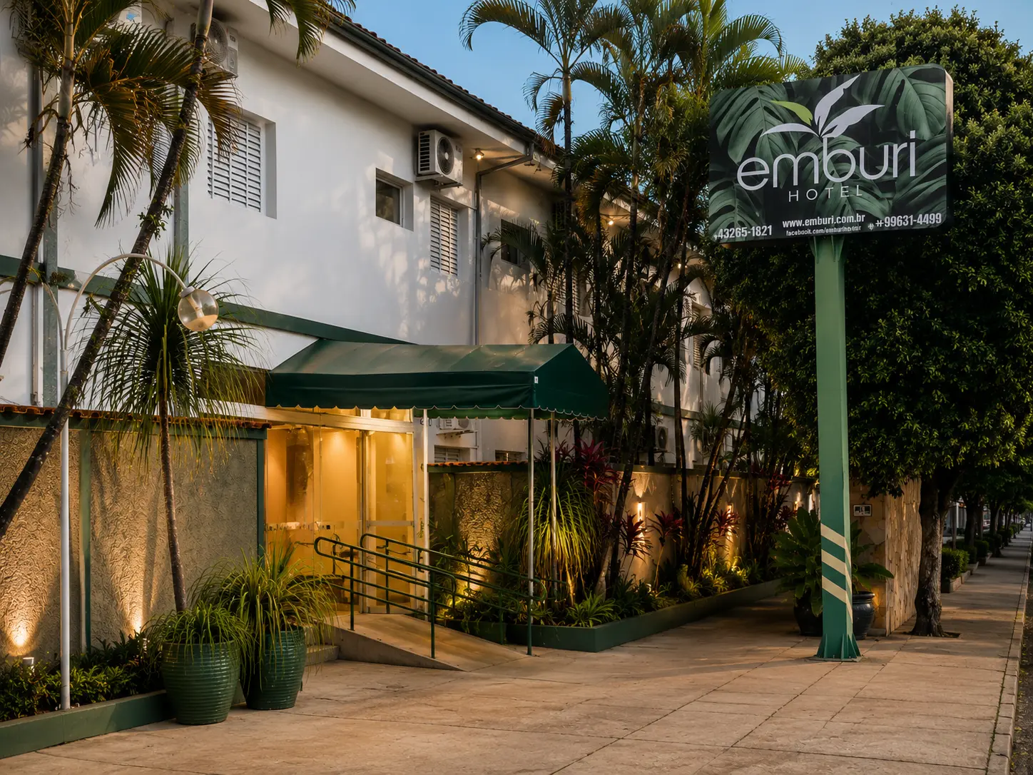 Fachada iluminada do Emburi Hotel em Piratininga, com entrada e totem da marca